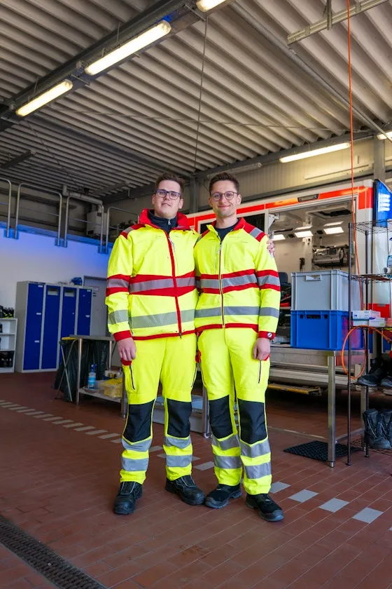 Zwei Männer die vor einem Rettungswagen stehen.